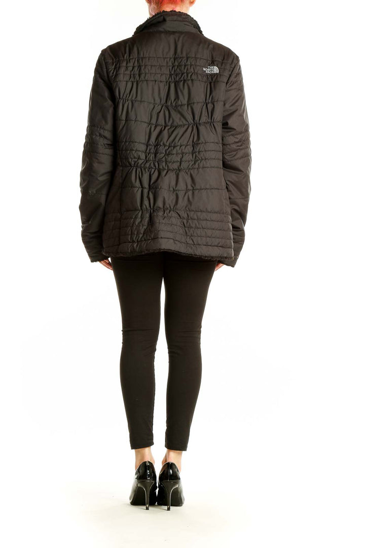 Back view of black quilted The North Face jacket on model