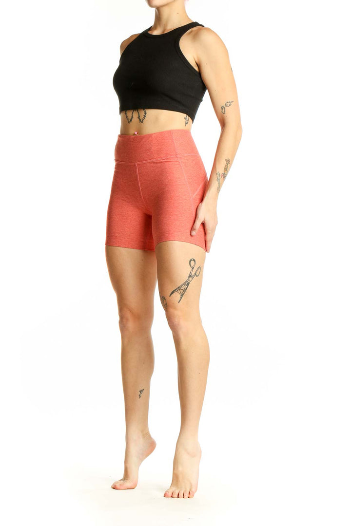 Front view of coral high-waisted workout shorts from Outdoor Voices