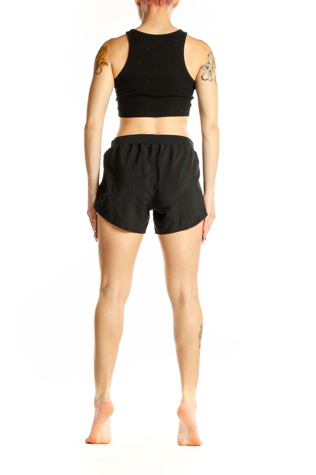 Side view of woman wearing black Under Armour athletic shorts and crop top
