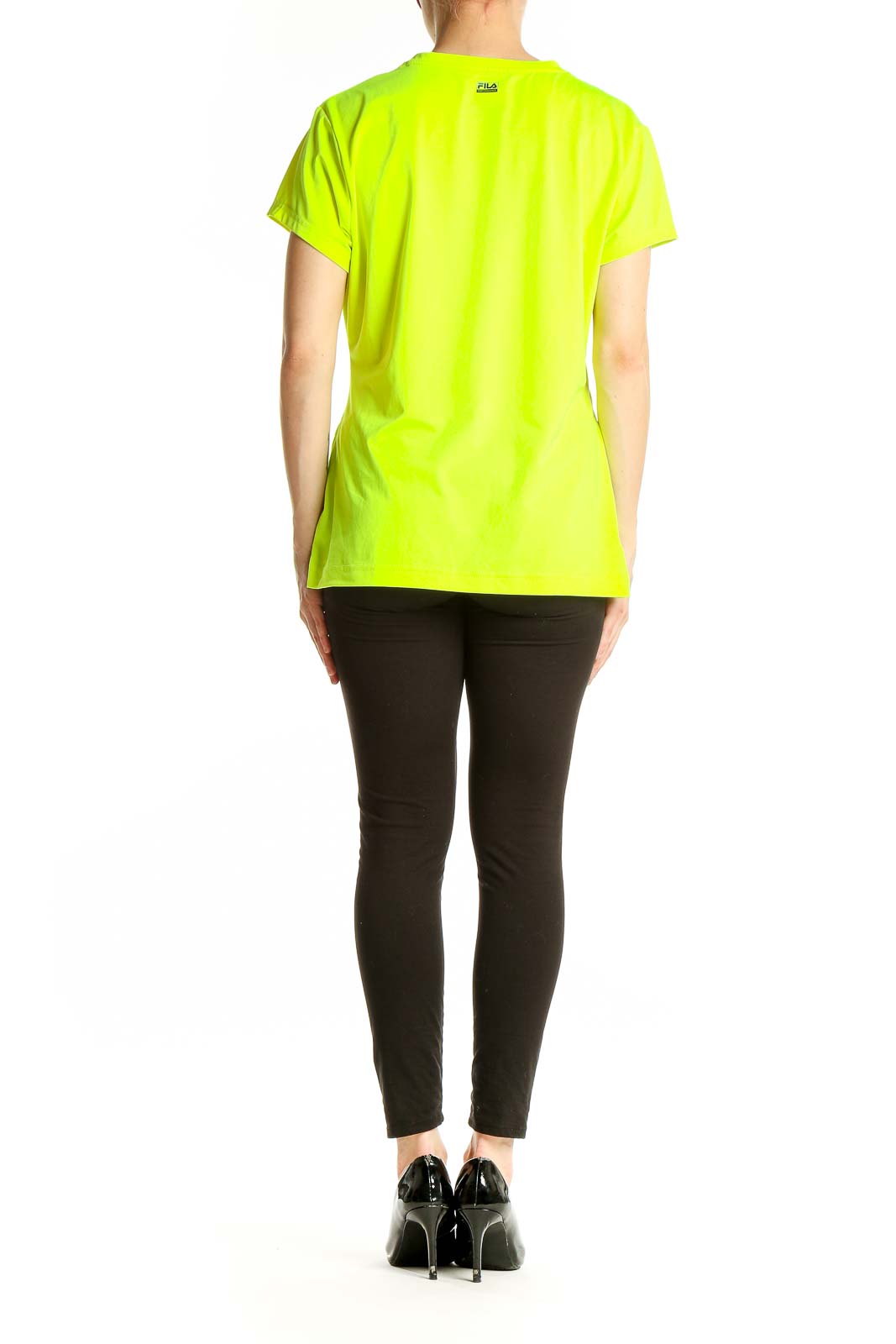 Side view of woman wearing neon yellow Fila V-neck athletic top with black pants