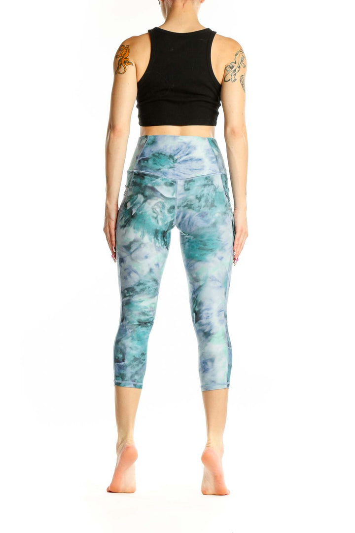 Side view of woman wearing teal tie-dye capri leggings and black crop top