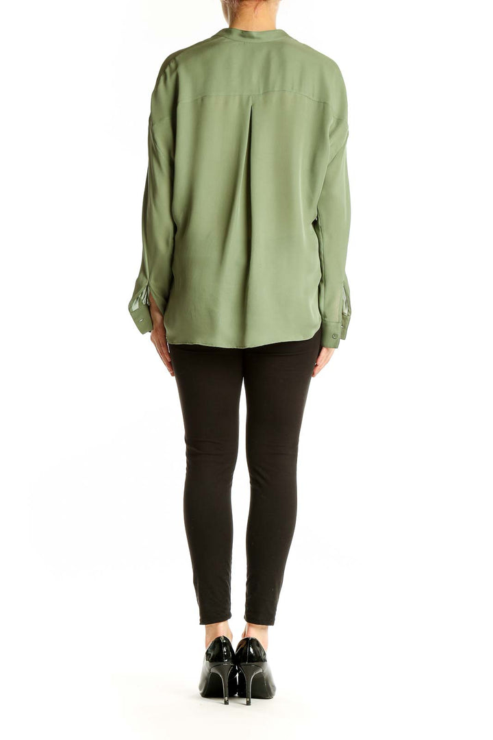 Side view of model wearing Vince sage green silk blouse with black pants