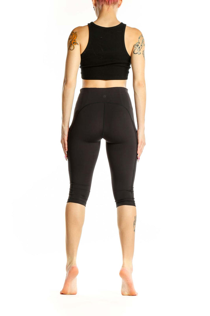 Side view of woman wearing black Athleta high-waisted capri leggings and crop top