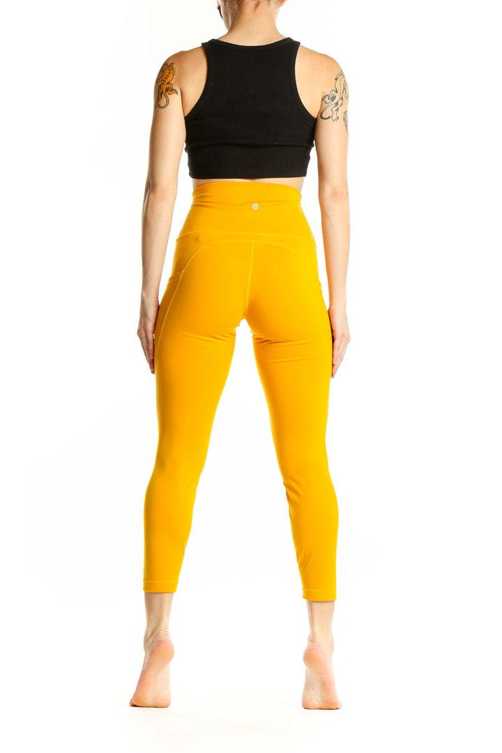 Side view of woman wearing yellow high-waisted compression leggings from 90 Degree with black crop top