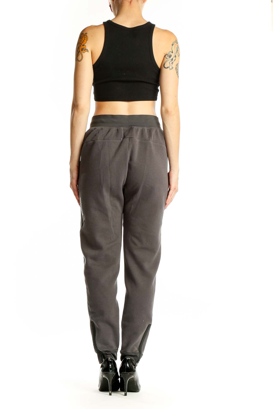 Side view of woman wearing gray Gymshark jogger pants and black crop top