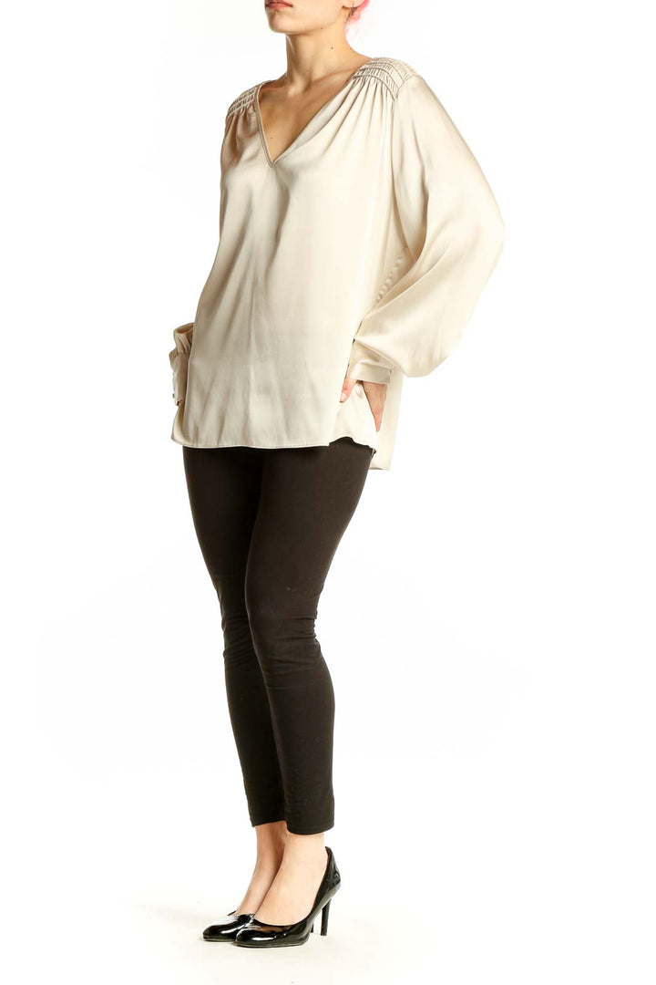 Front view of cream V-neck blouse with gathered shoulders