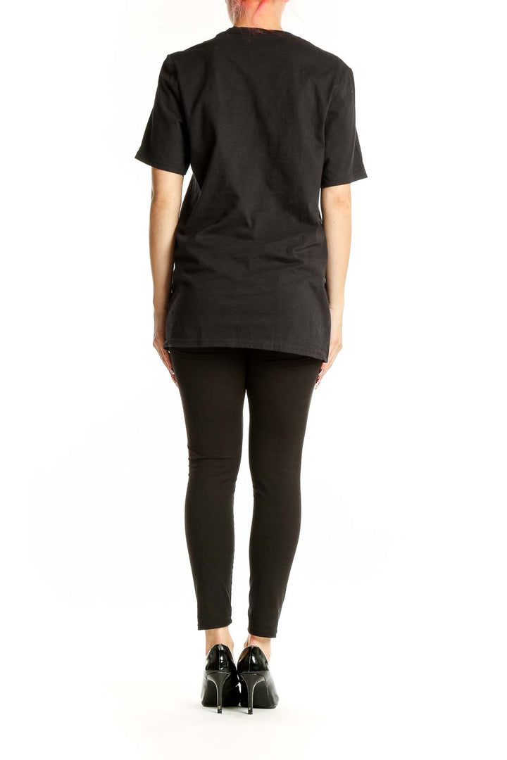 Side view of woman wearing black Adidas logo t-shirt with black pants