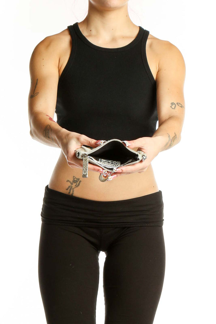 Side view of Calvin Klein silver snakeskin wristlet clutch held by model