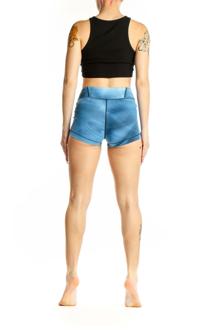 Side view of woman wearing blue Reebok athletic shorts and black crop top