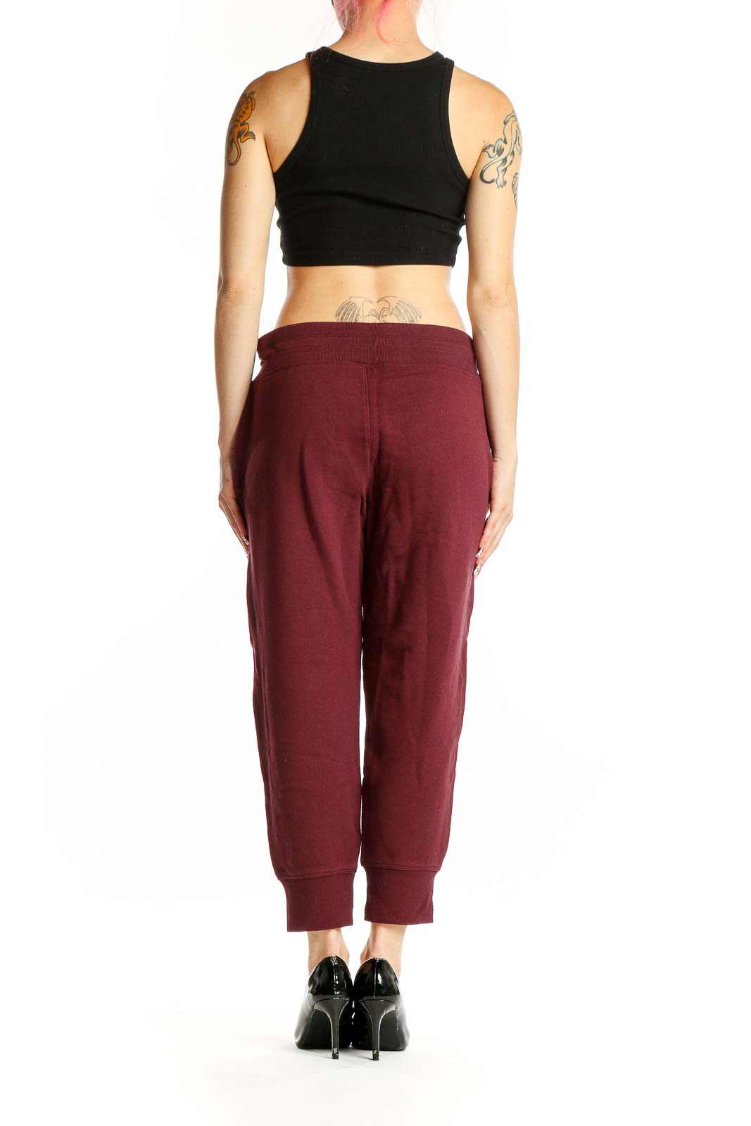 Side view of model wearing DKNY Sport burgundy joggers and black crop top
