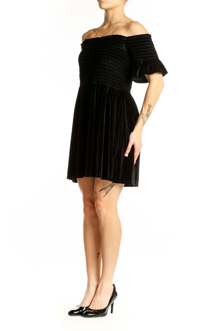 Front view of black velvet off-shoulder mini dress with smocked bodice