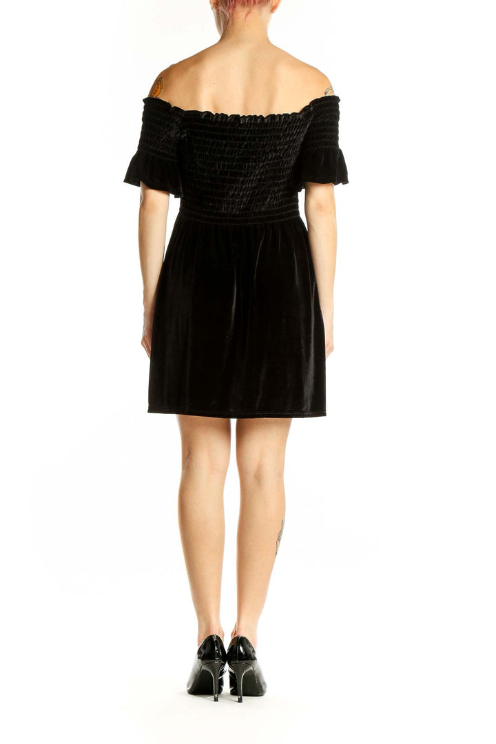 Side view of black velvet off-shoulder mini dress showing flutter sleeves