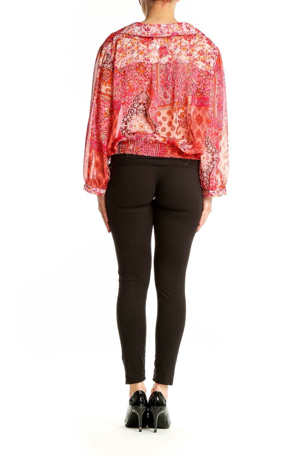 Back view of orange floral paisley wrap blouse on model with black pants