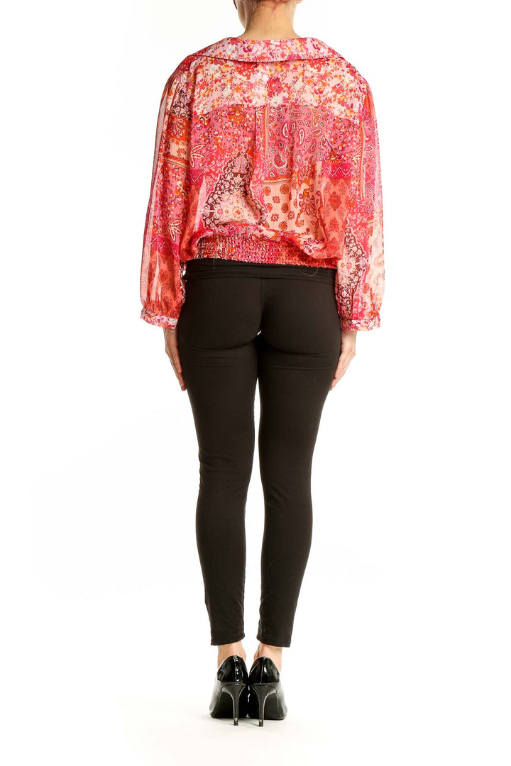 Back view of orange floral paisley wrap blouse on model with black pants