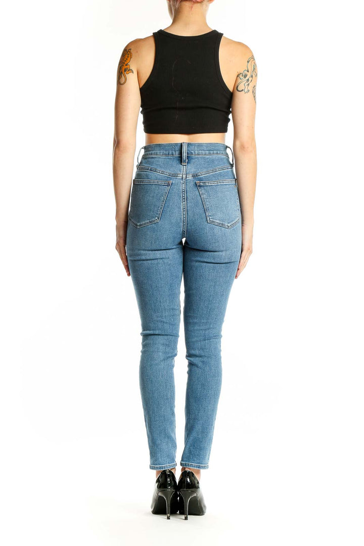 Side view of Madewell light blue high-waisted skinny jeans on model with black crop top