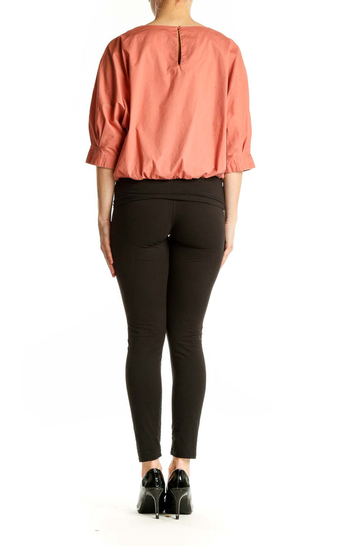 Side view of coral Prologue top showing puff sleeves and relaxed fit