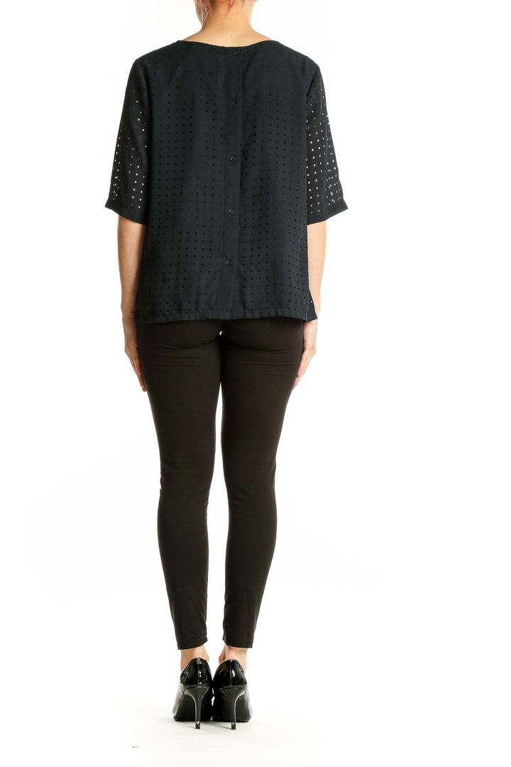 Side view of woman wearing Banana Republic black perforated boxy blouse with black pants
