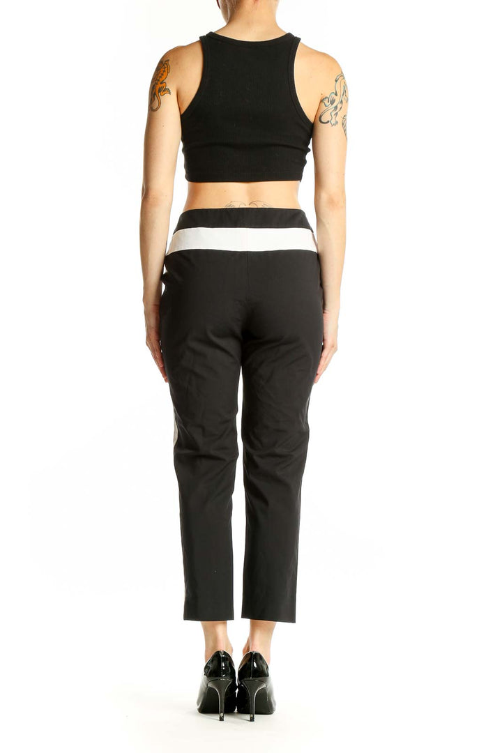 Side view of black cropped trousers with white side stripes on model