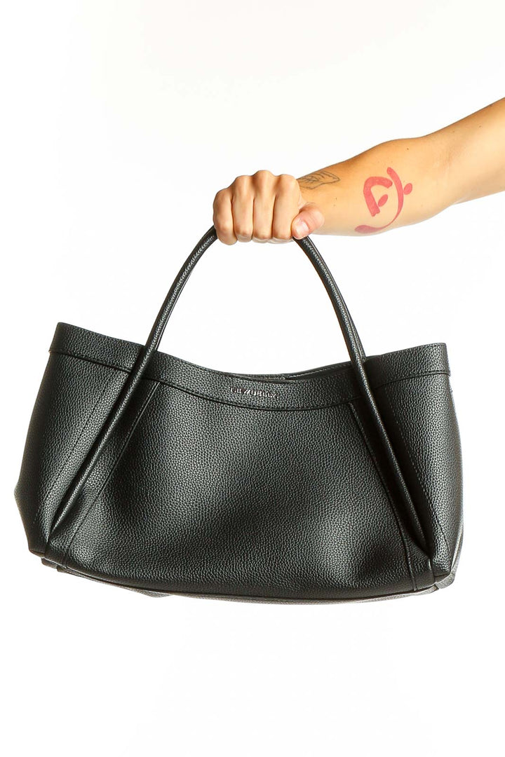 Black leather shoulder bag from NEWBELLA held by model's hand