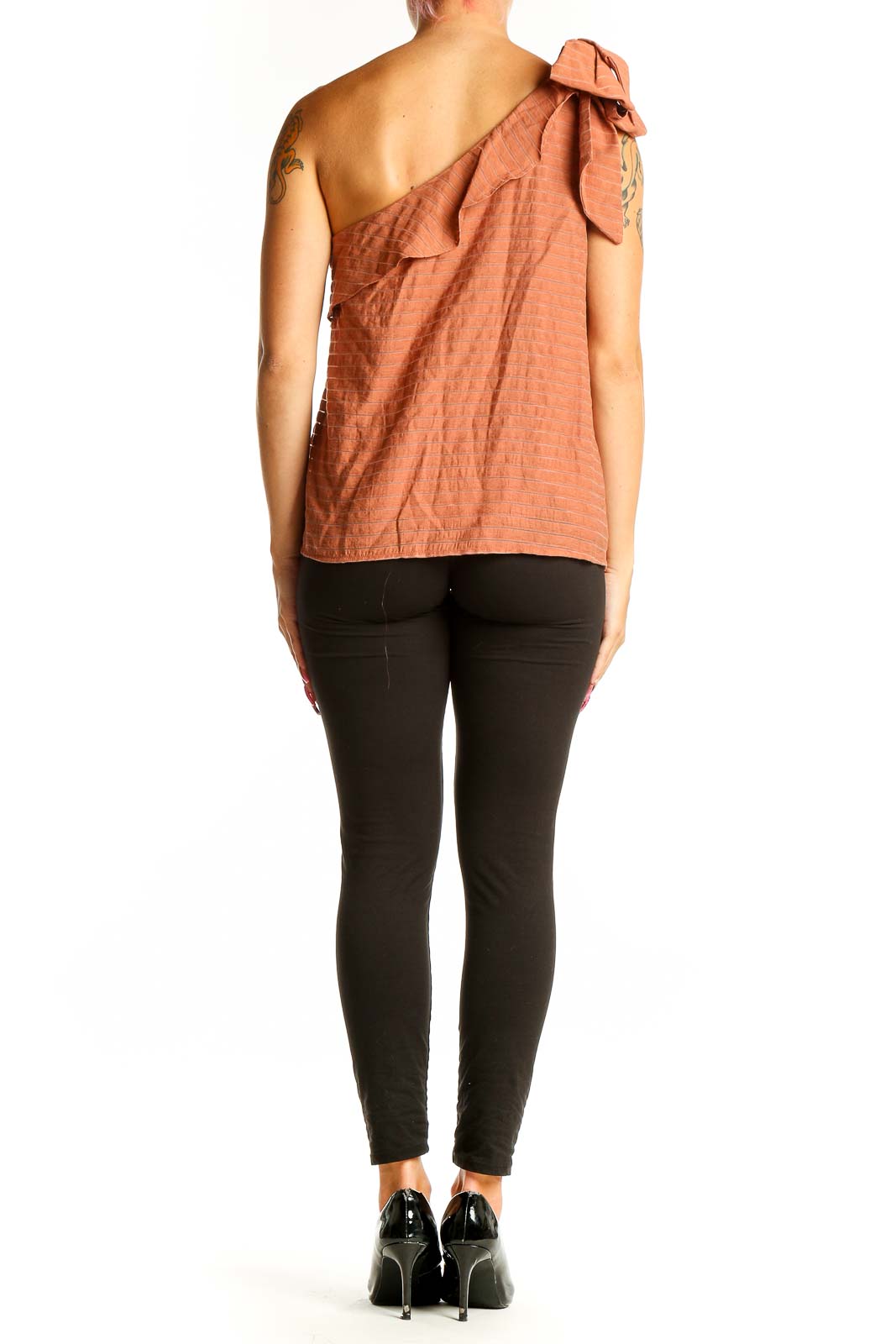 Side view of terracotta one-shoulder ruffled top by Nine West with black pants