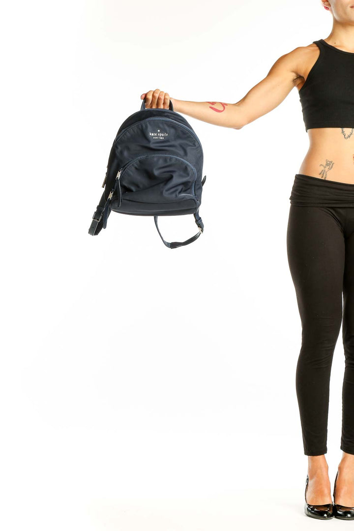 Front view of Kate Spade navy nylon backpack with logo and front zip pocket