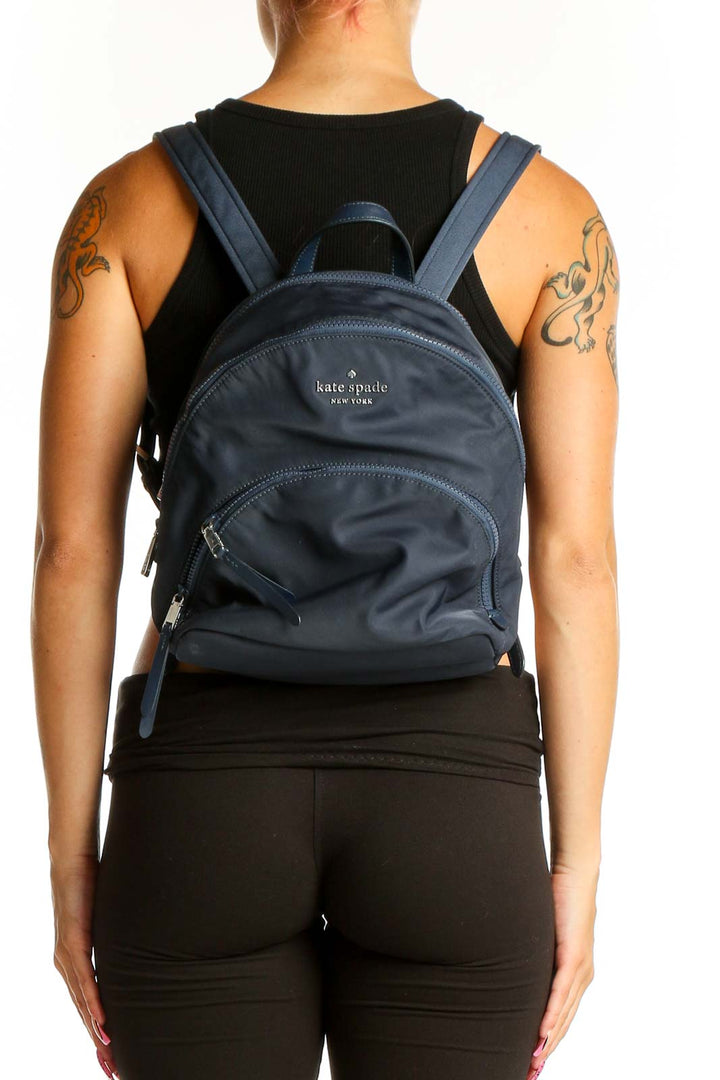 Front view of Kate Spade navy nylon backpack with logo and front zip pocket