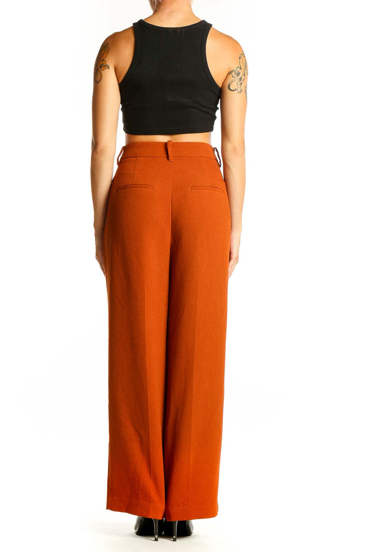 Side view of woman wearing burnt orange wide-leg trousers with black crop top