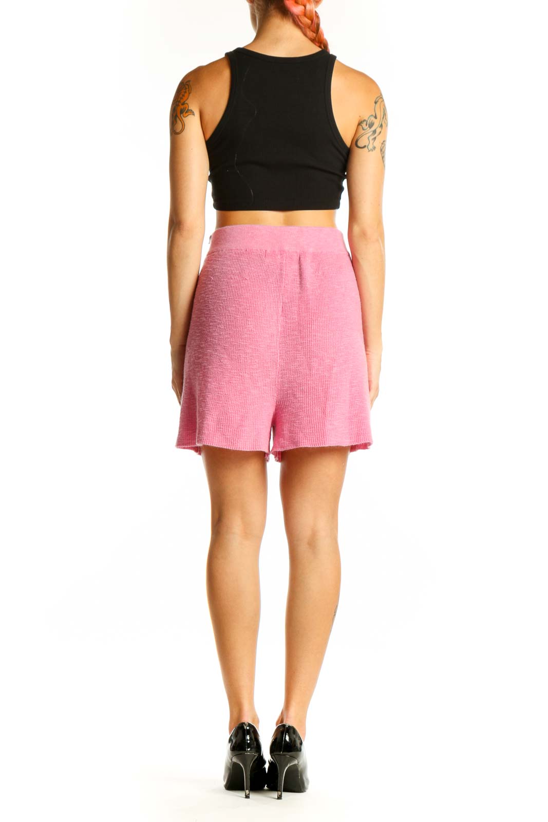 Side view of woman wearing pink FP Beach shorts with black crop top