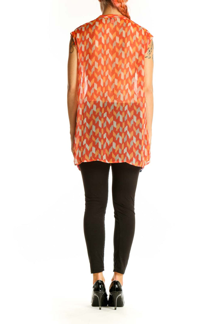Side view of model wearing Lucky Brand orange geometric print sleeveless blouse with black pants