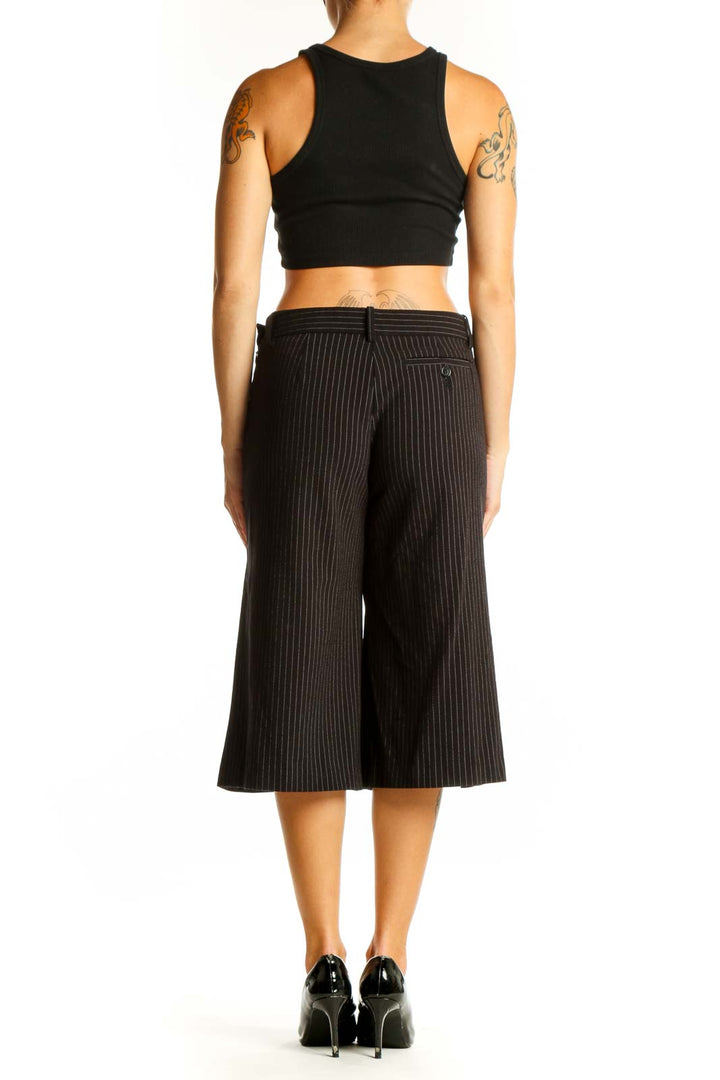 Side view of BCBG MaxAzria black pinstriped cropped wide-leg trousers on model with black crop top