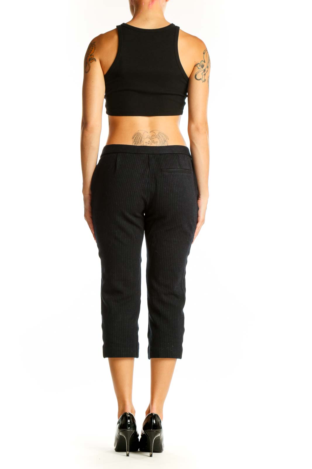 Side view of woman wearing Theory black pinstriped cropped dress pants with black top