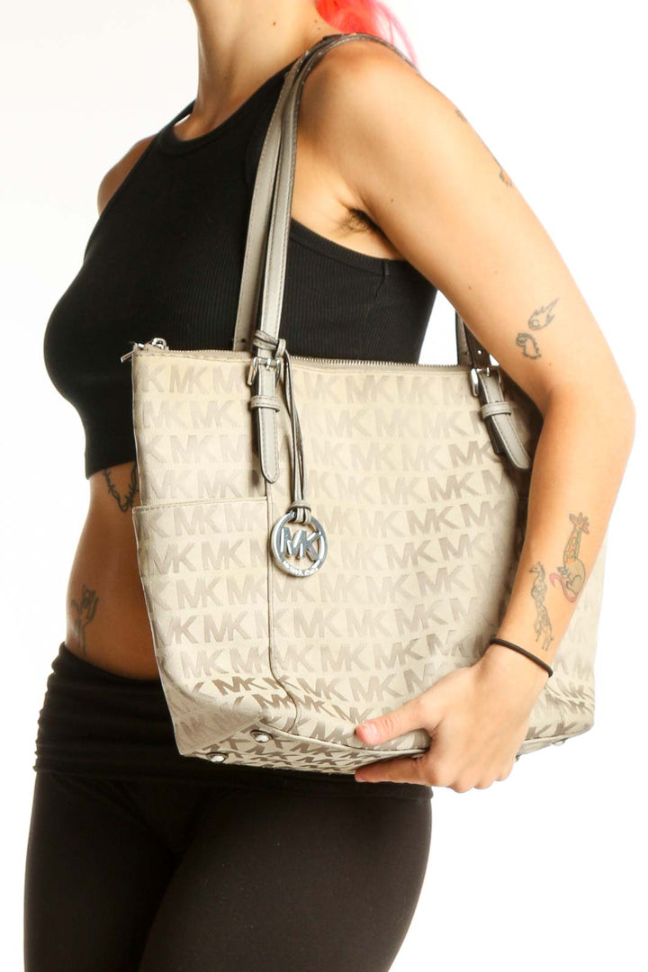 Front view of Michael Kors beige monogram tote bag with MK charm