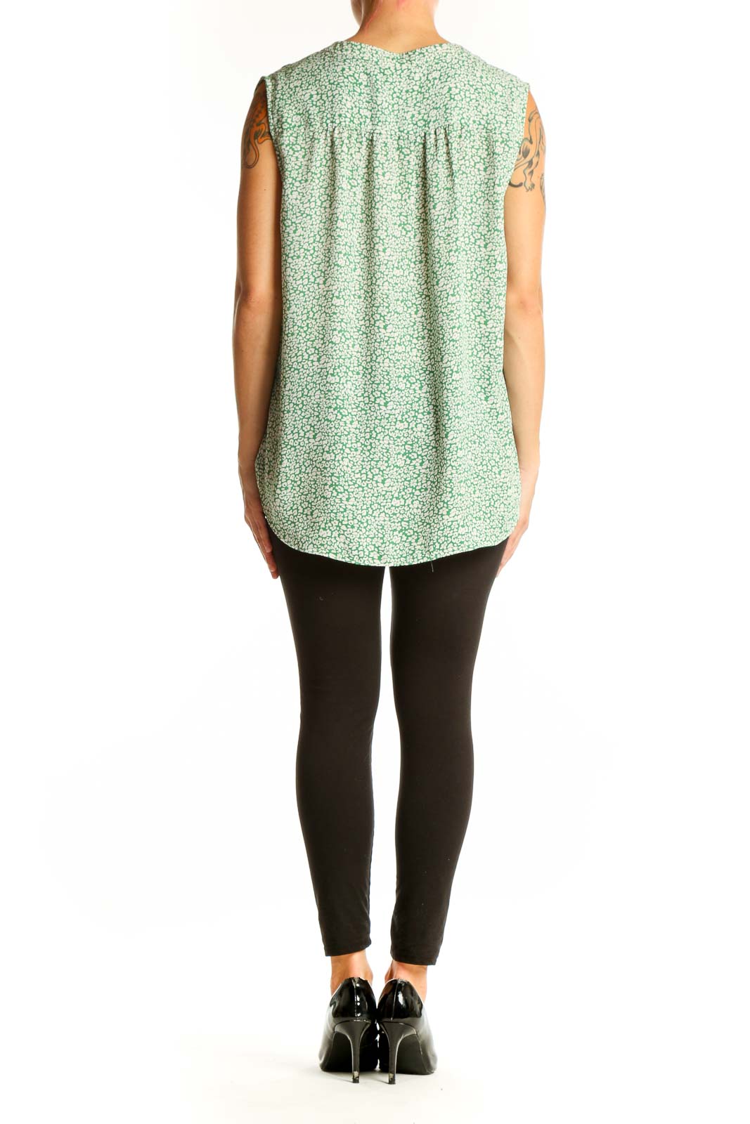 Side view of model wearing Vince Camuto green floral sleeveless blouse with black pants