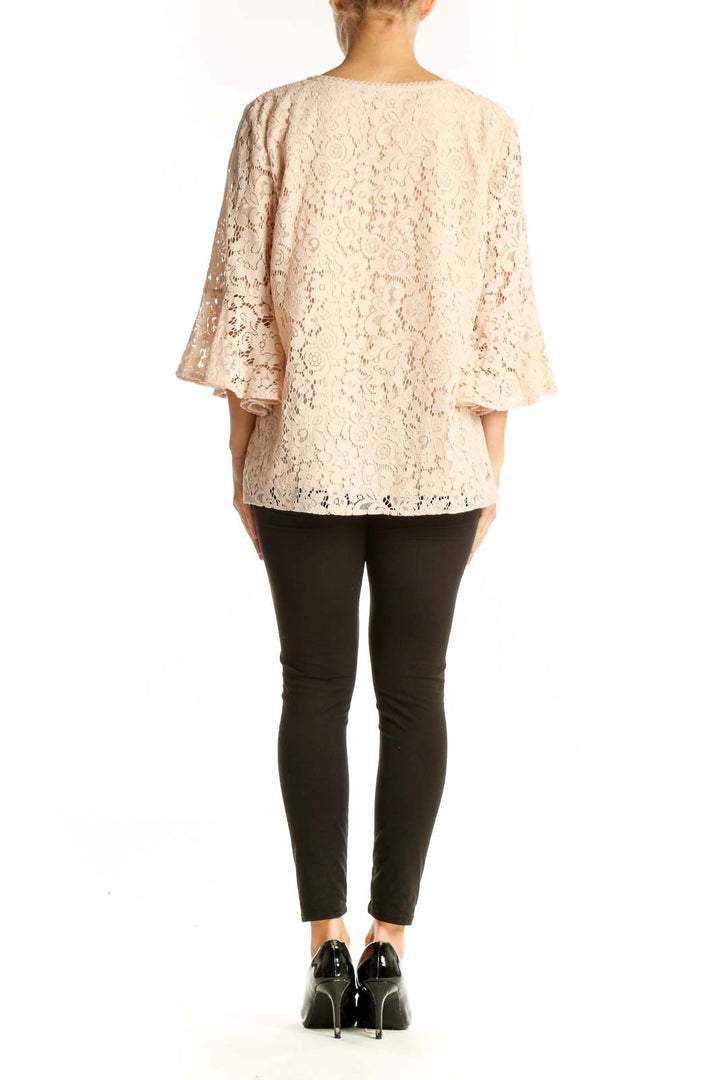 Side view of blush lace bell sleeve V-neck blouse from LOFT Outlet with black pants
