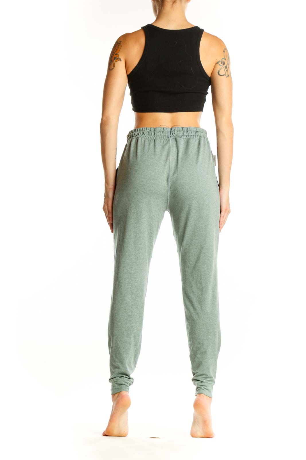 Side view of woman wearing sage green Vuori jogger pants with black crop top