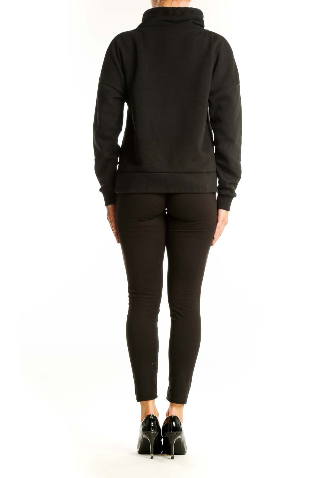 Side view of model wearing black cowl neck sweatshirt with black pants