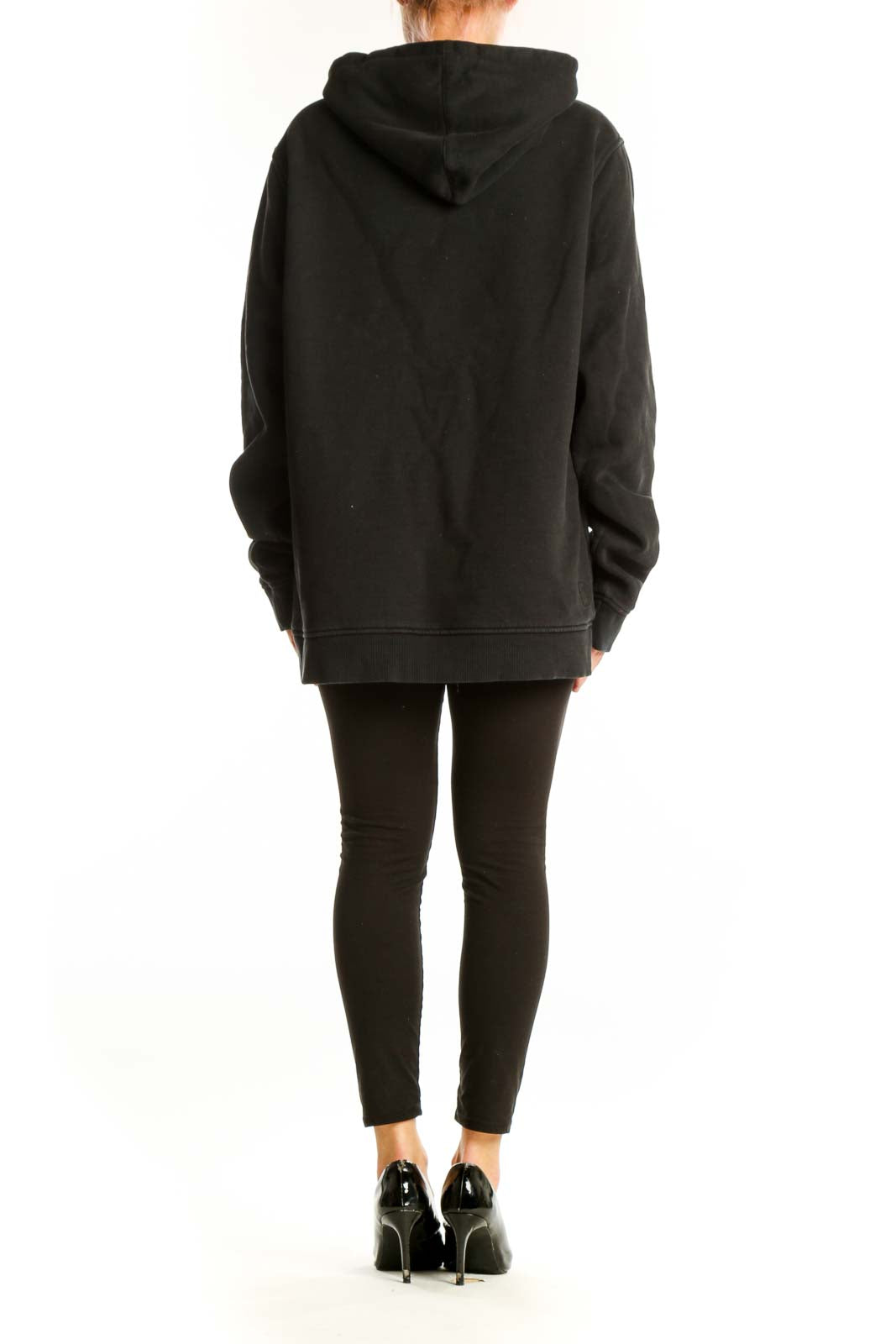 Back view of black Vuori oversized hoodie on model with leggings
