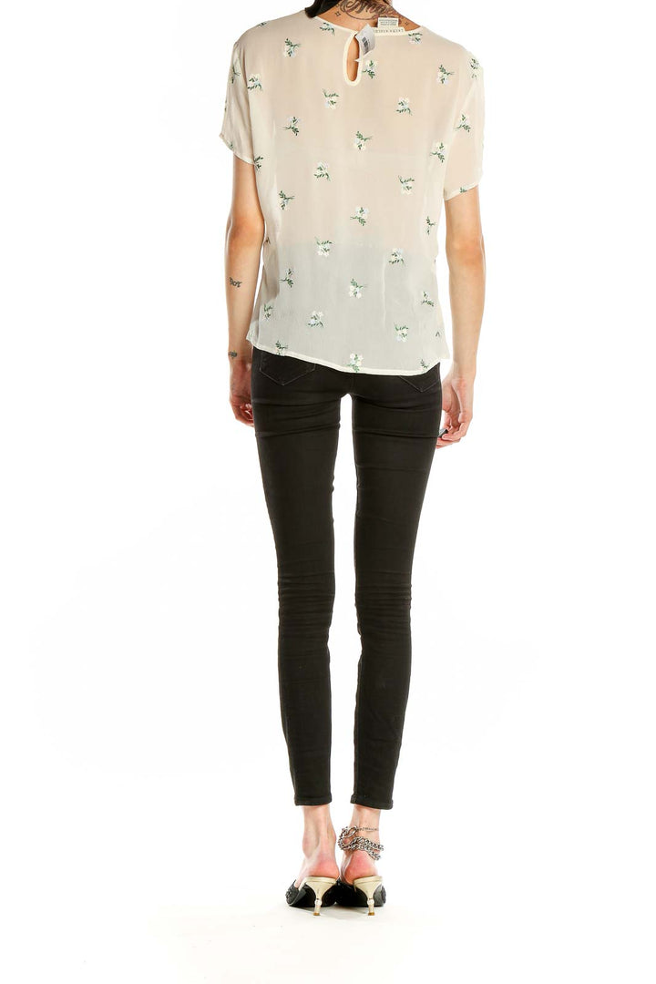 Back view of Laura Ashley cream floral print blouse on model with black pants