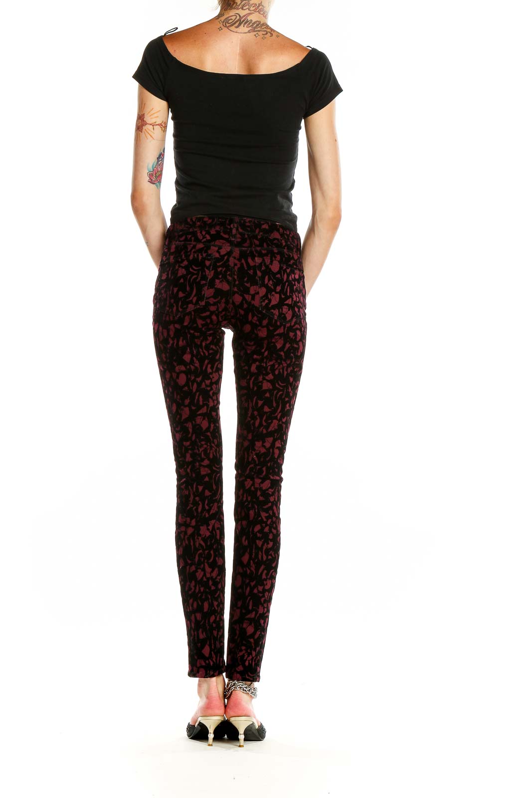 Side view of model wearing J Brand burgundy floral velvet skinny pants with black top