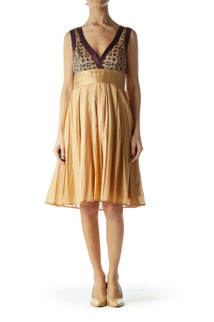 Front view of gold Catherine Malandrino cocktail dress with patterned bodice and pleated skirt