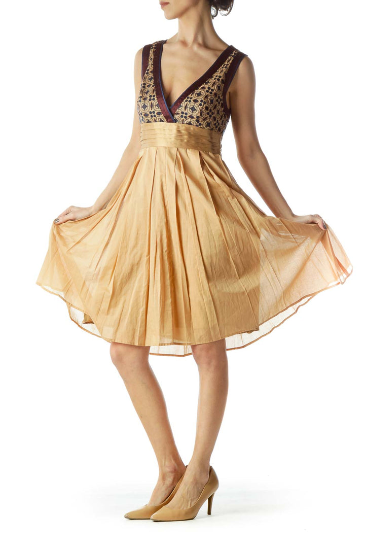 Front view of gold Catherine Malandrino cocktail dress with patterned bodice and pleated skirt