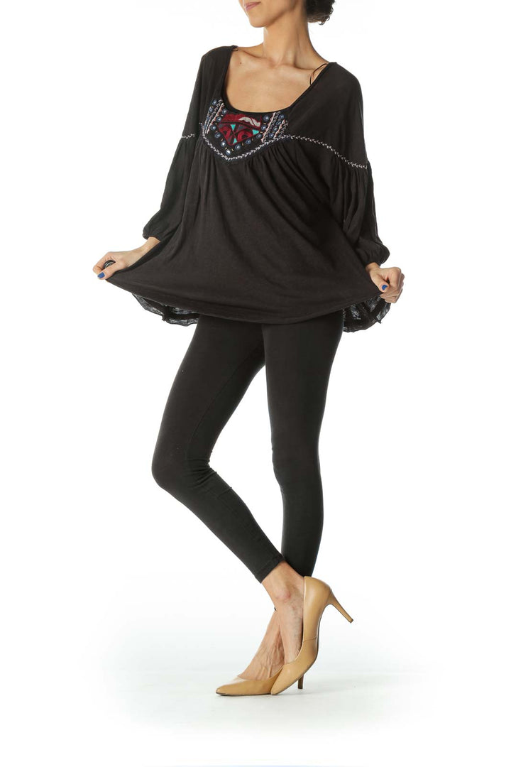 Front view of Free People black peasant top with colorful embroidery and flowy sleeves