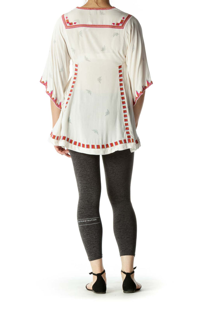 Back view of white Free People tunic top showing flowy design and red trim details