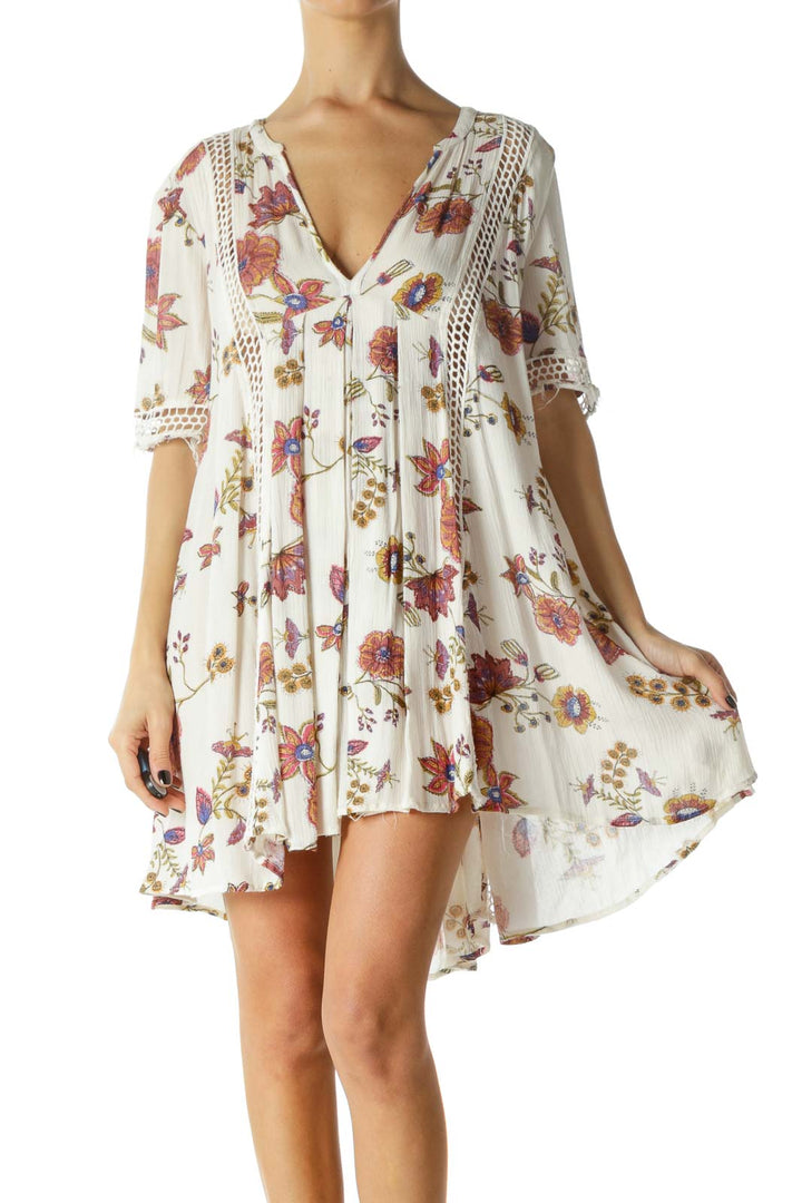 Front view of white floral Free People mini dress with crochet trim and V-neckline