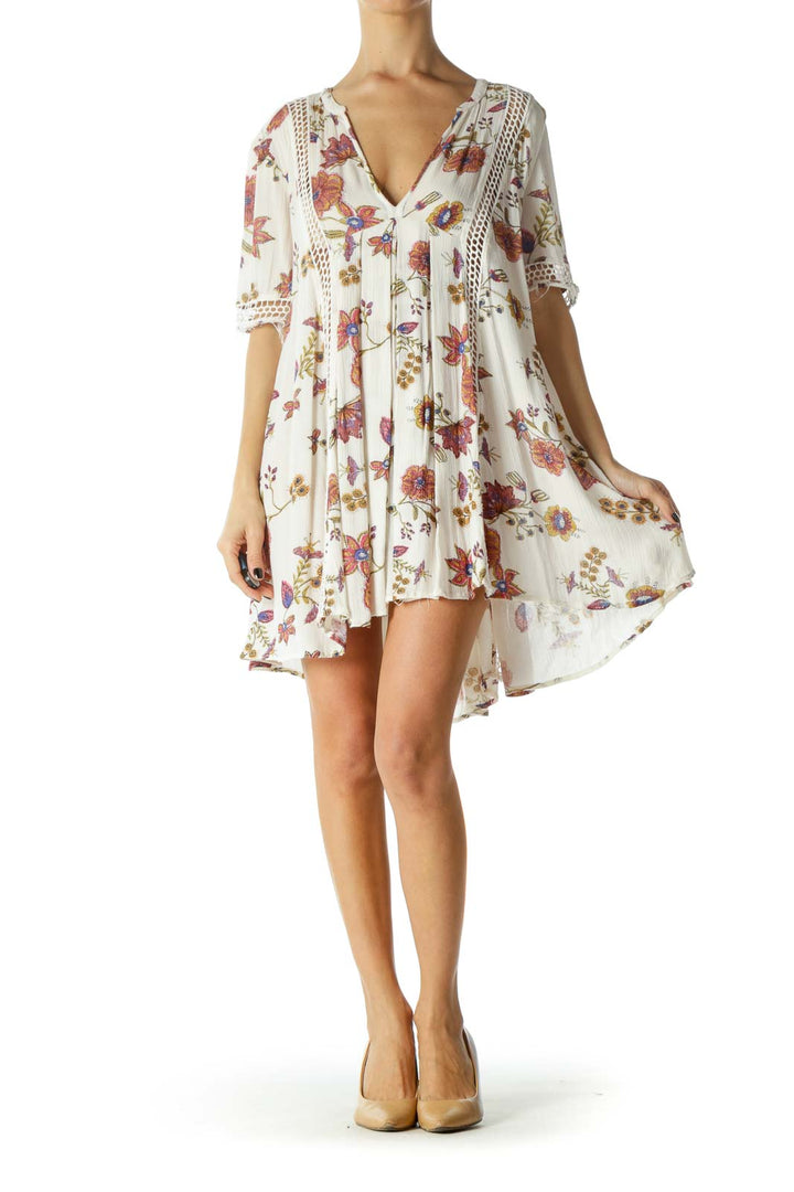 Front view of white floral Free People mini dress with crochet trim and V-neckline