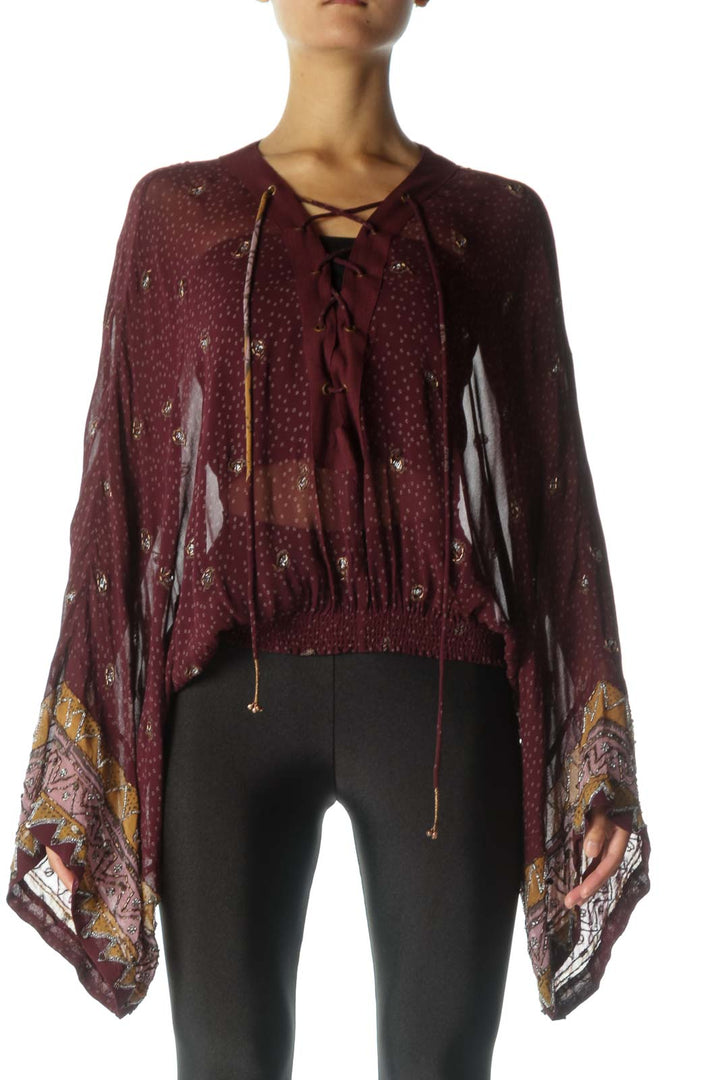 Front view of burgundy Free People top with lace-up neckline and bell sleeves