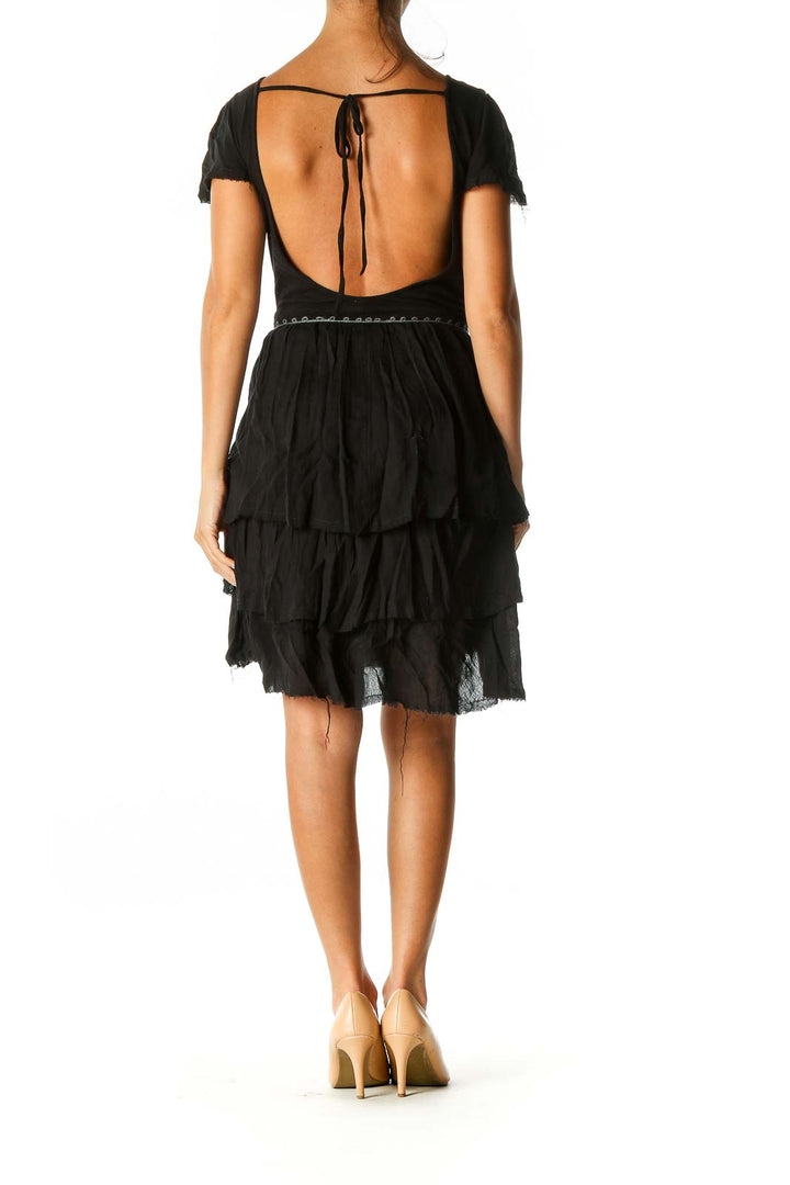 Back view of black Free People mini dress showing open back design with tie closure