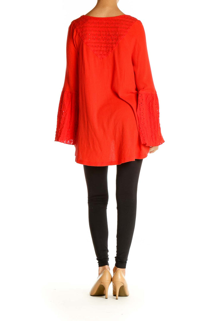 Back view of red Free People tunic top showing flowy silhouette and lace-trimmed bell sleeves