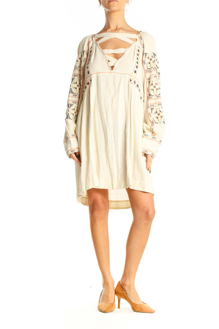 Front view of cream Free People mini dress with embroidered sleeves and crisscross neckline