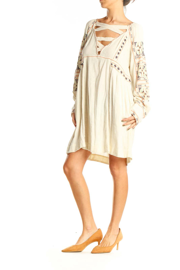 Front view of cream Free People mini dress with embroidered sleeves and crisscross neckline